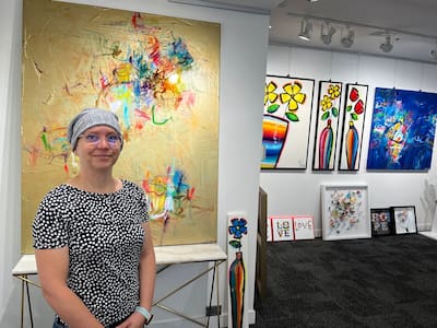 La artista Mélanie Simard posa con varios de sus cuadros que estarán disponibles durante la Noche de las Galerías. El lienzo de la derecha (azul) se titula “Siempre hay esperanza” y el de la izquierda (dorado) se titula “Nuestras preciosas luchas”.