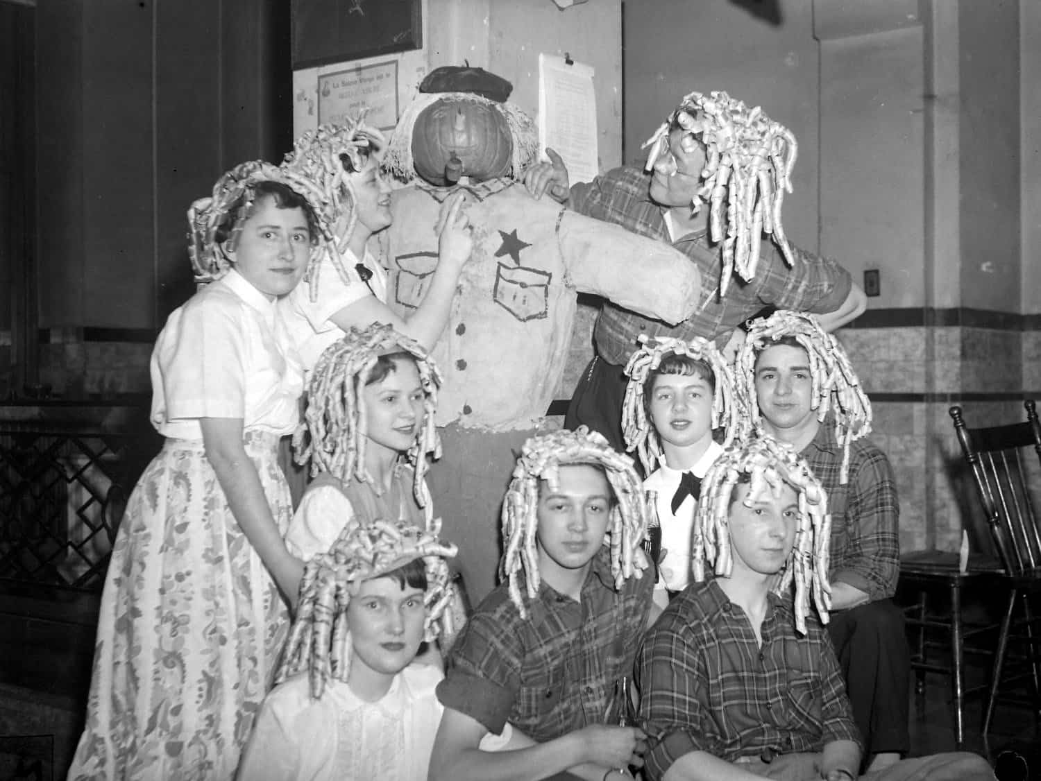 Des Québécoises en costume réunies autour d'un épouvantail, lors d'une soirée d'Halloween, dans les années 1950.