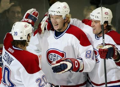 Marcel Hossa (c) do Montreal Canadiens comemora seu gol da vitória contra o New York Rangers com os companheiros Richard Zednik (20) e Craig Rivet (R) durante o terceiro período da NHL em Montreal em 9 de janeiro de 2003. Os Canadiens venceram o Rangers por 3-2.