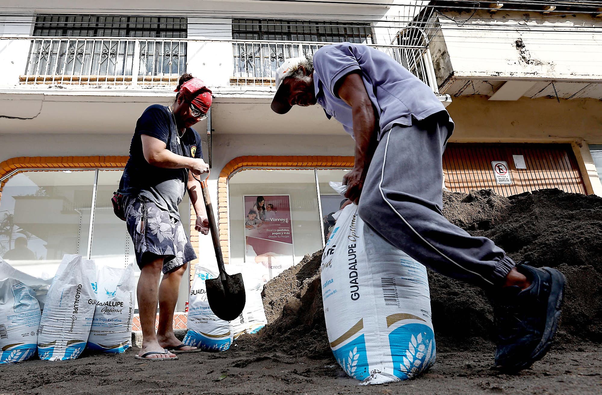 Un homme remplit des sacs de sable pour protéger son commerce.