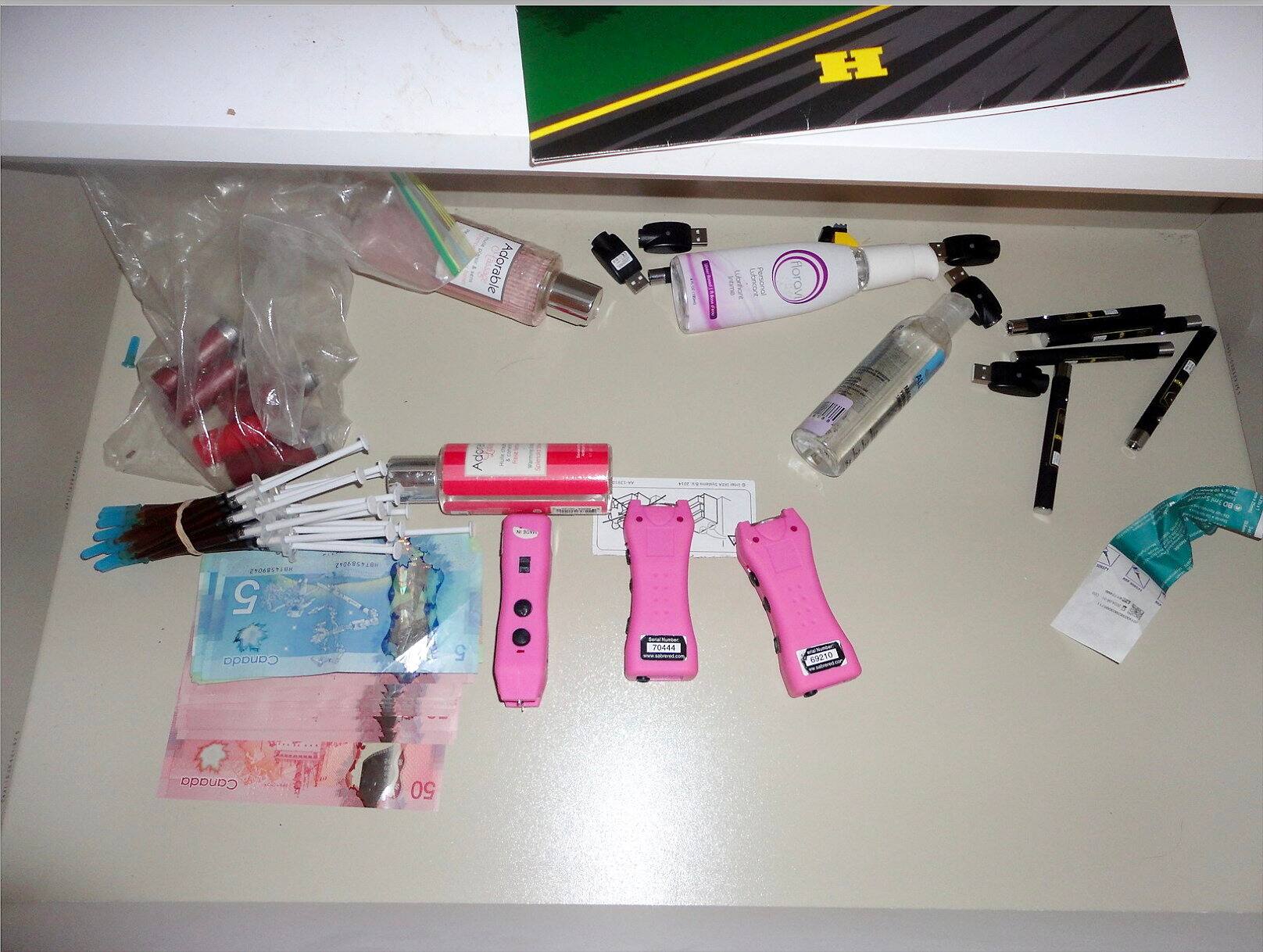 Foto de tres armas con pulso eléctrico rosa, jeringas y paquetes de plata que se encuentran en Daniel Alexander Franco-Murillo.