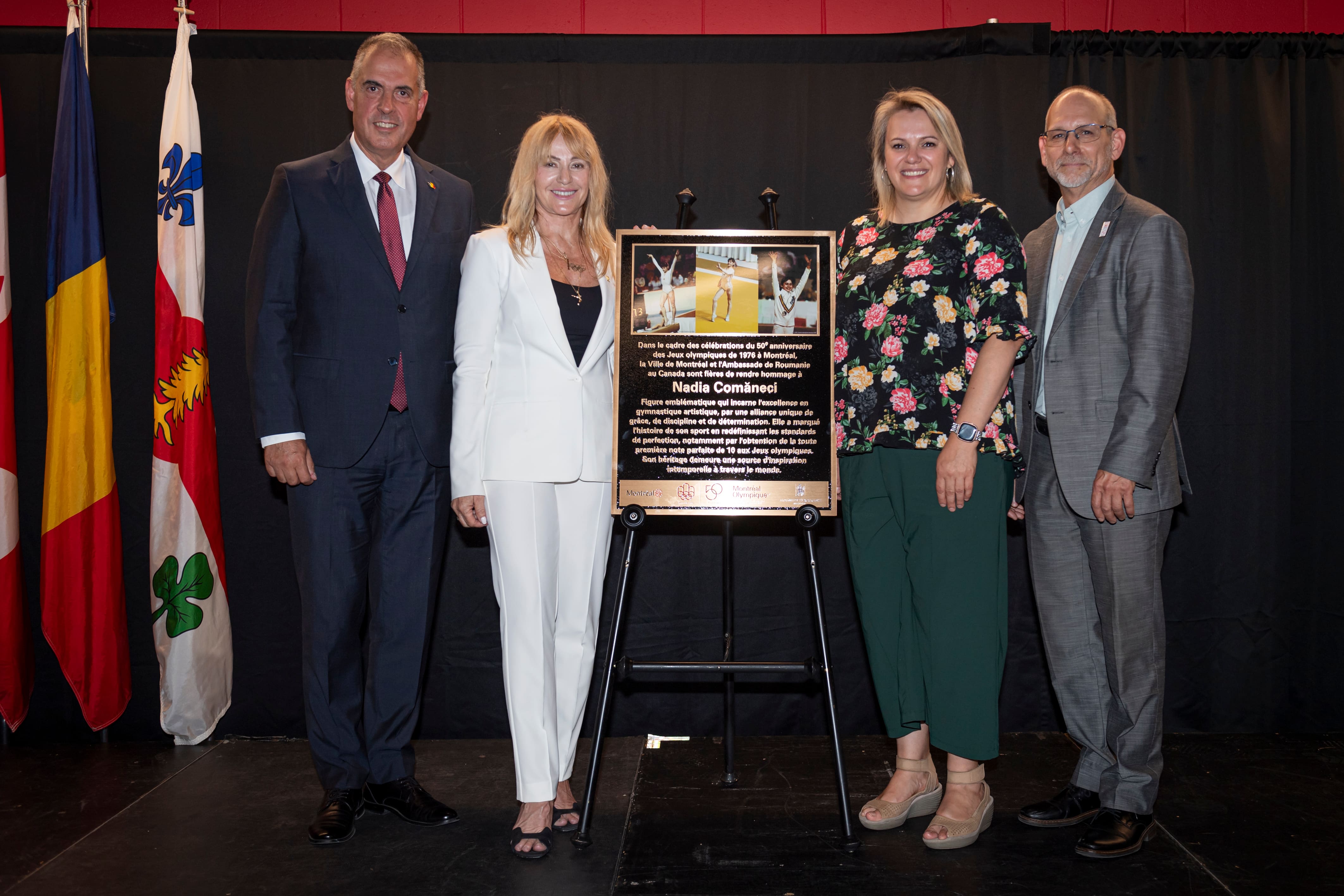 Nadia Comaneci est entourée de Bogdan Mănoiu (ambassadeur de la Roumanie au Canada), de même que de Christine Black et Luc Denis, à titre de représentants de la Ville de Montréal, le vendredi 31 juillet 2026, durant le dévoilement d’une plaque commémorative au centre Claude-Robillard.