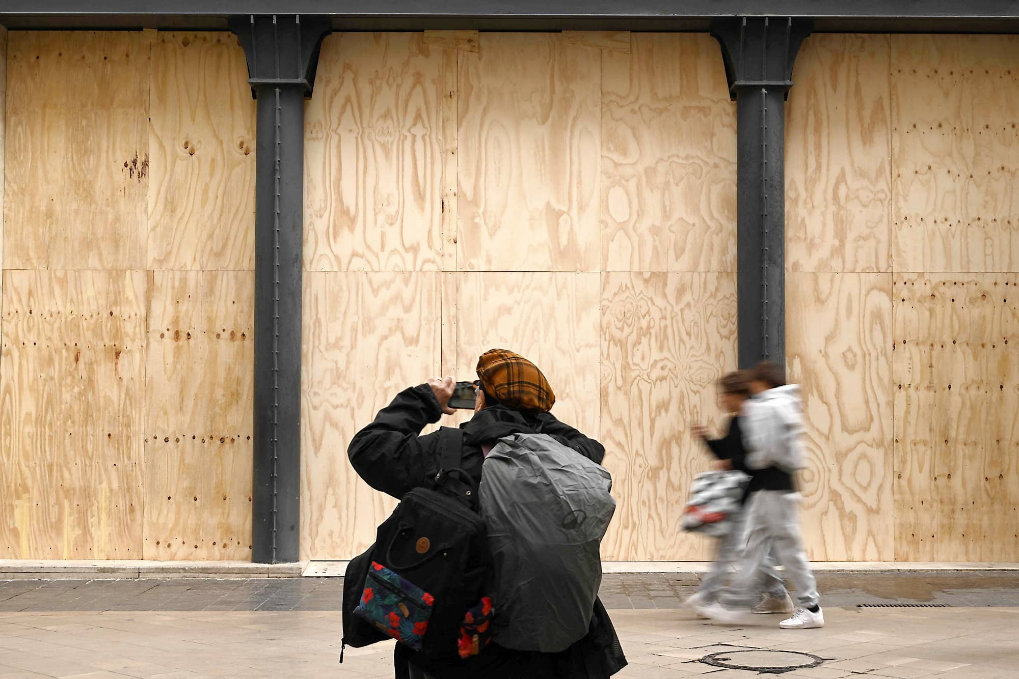 Un passant prenait une photo des vitres placardées d'un commerce, vendredi, en prévision des manifestations de samedi, à Bordeaux.