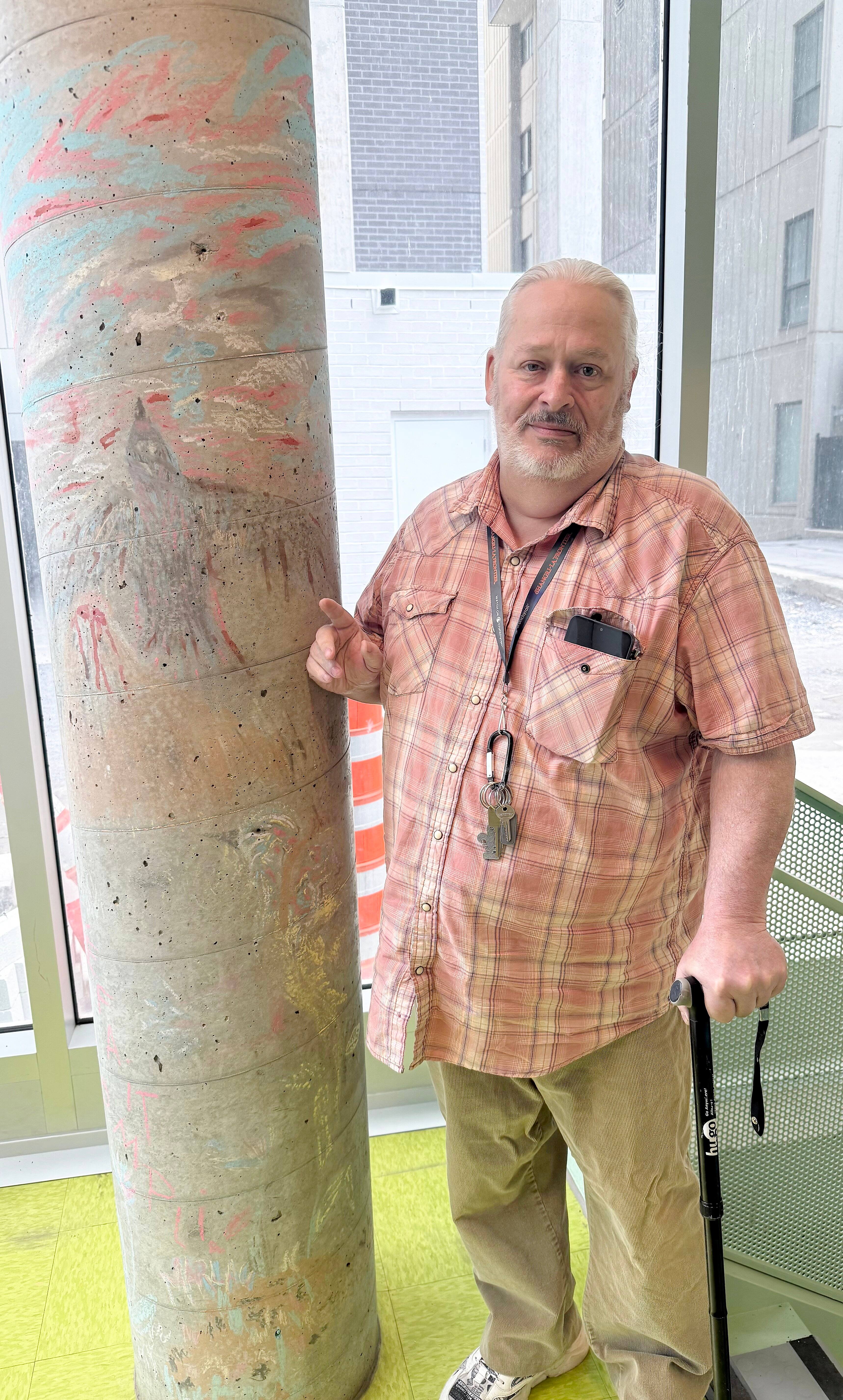 Michel Boisvert, un locataire dans Le Christin, se tient près d'une colonne où l'on aperçoit encore un dessin de son ex-voisin décédé.