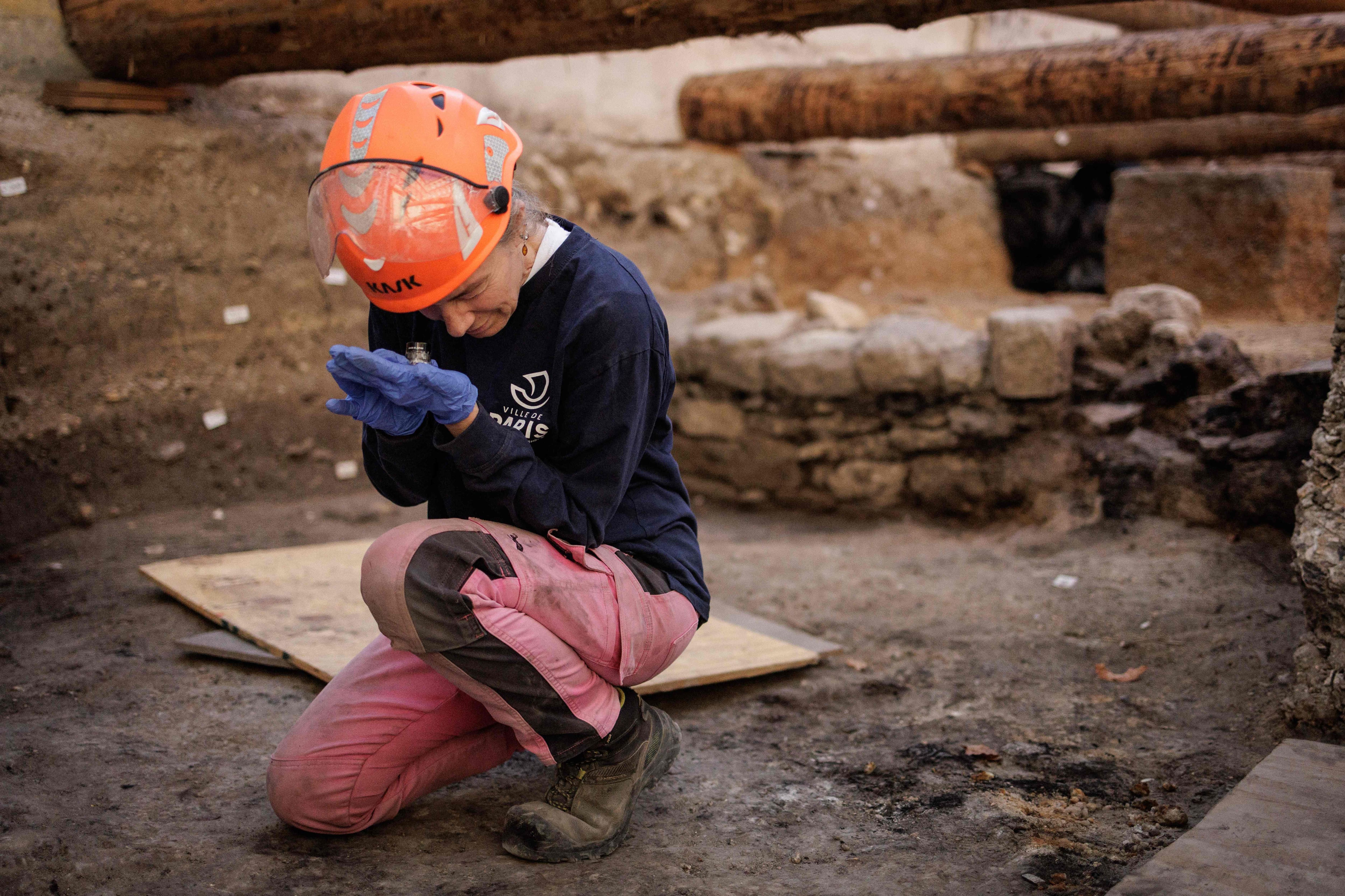 Elodie Perugini, archéologue pour la ville de Paris, examine une pièce gauloise à l'aide d'une loupe lors de fouilles sur un site archéologique situé sous l'hôpital Hôtel-Dieu, sur l'île de la Cité, au cœur de Paris, le 23 septembre 2026. Un mur gallo-romain de Lutèce a récemment été mis au jour sur ce site.