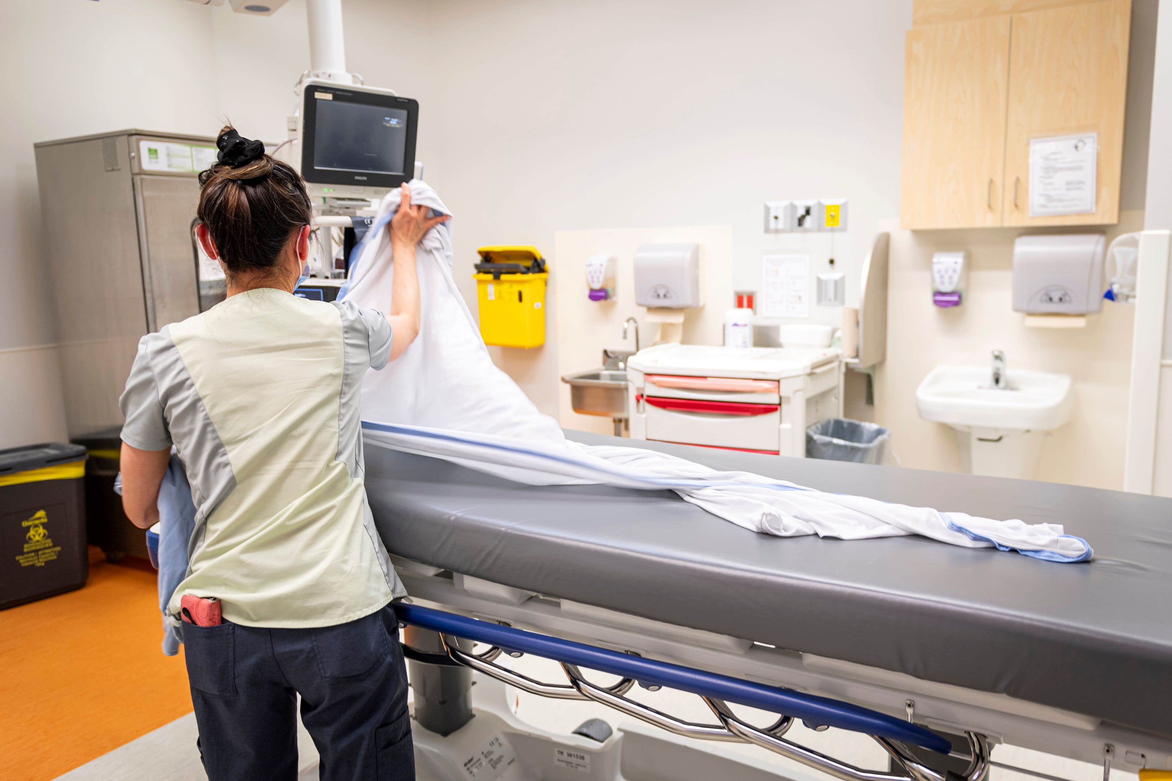 Une employée des urgences de l’Hôpital de Montréal recouvre une civière d'un drap.
