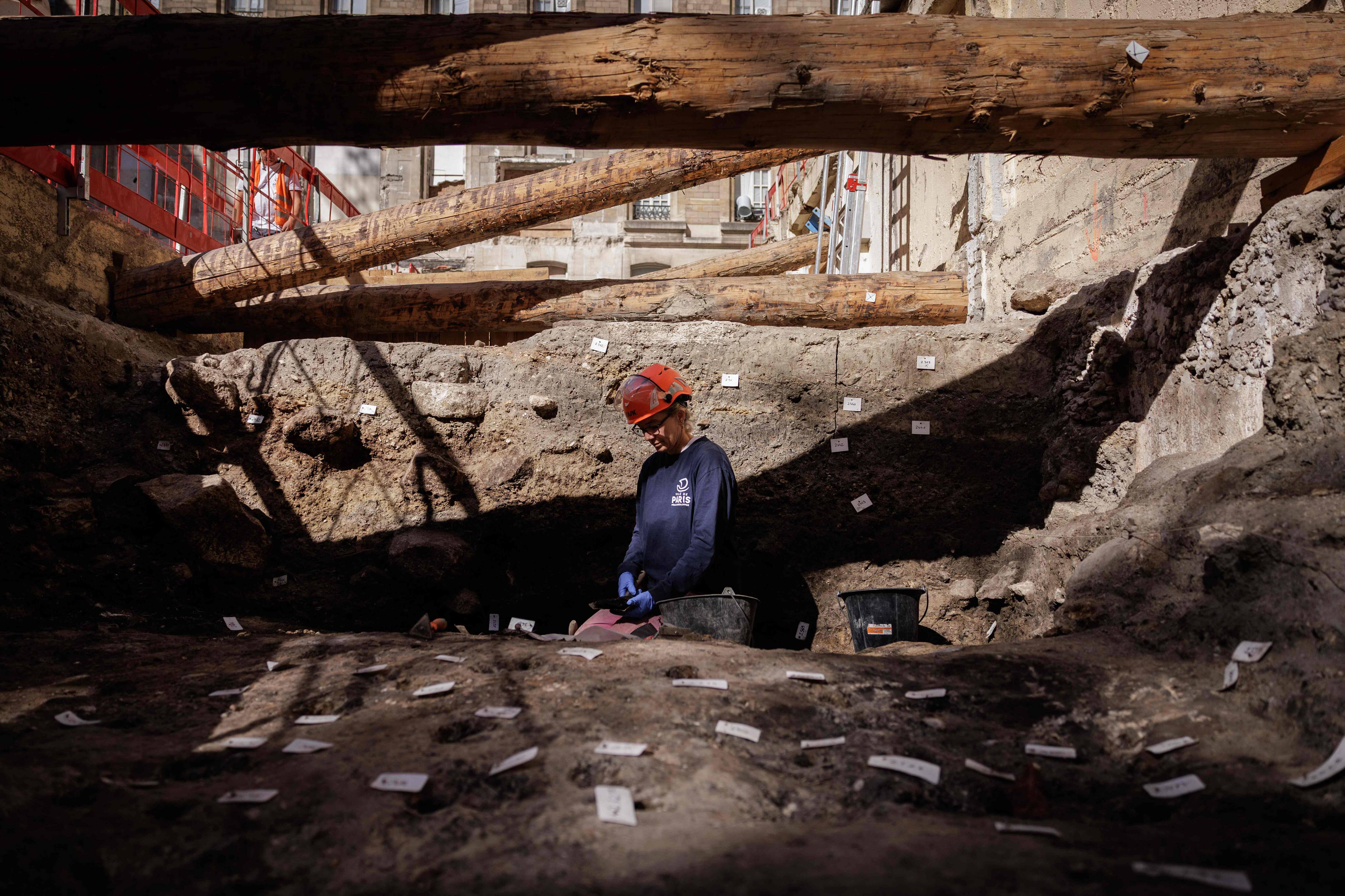 Elodie Perugini, archéologue pour la ville de Paris, examine une pièce gauloise à l'aide d'une loupe lors de fouilles sur un site archéologique situé sous l'hôpital Hôtel-Dieu, sur l'île de la Cité, au cœur de Paris, le 23 septembre 2026. Un mur gallo-romain de Lutèce a récemment été mis au jour sur ce site.