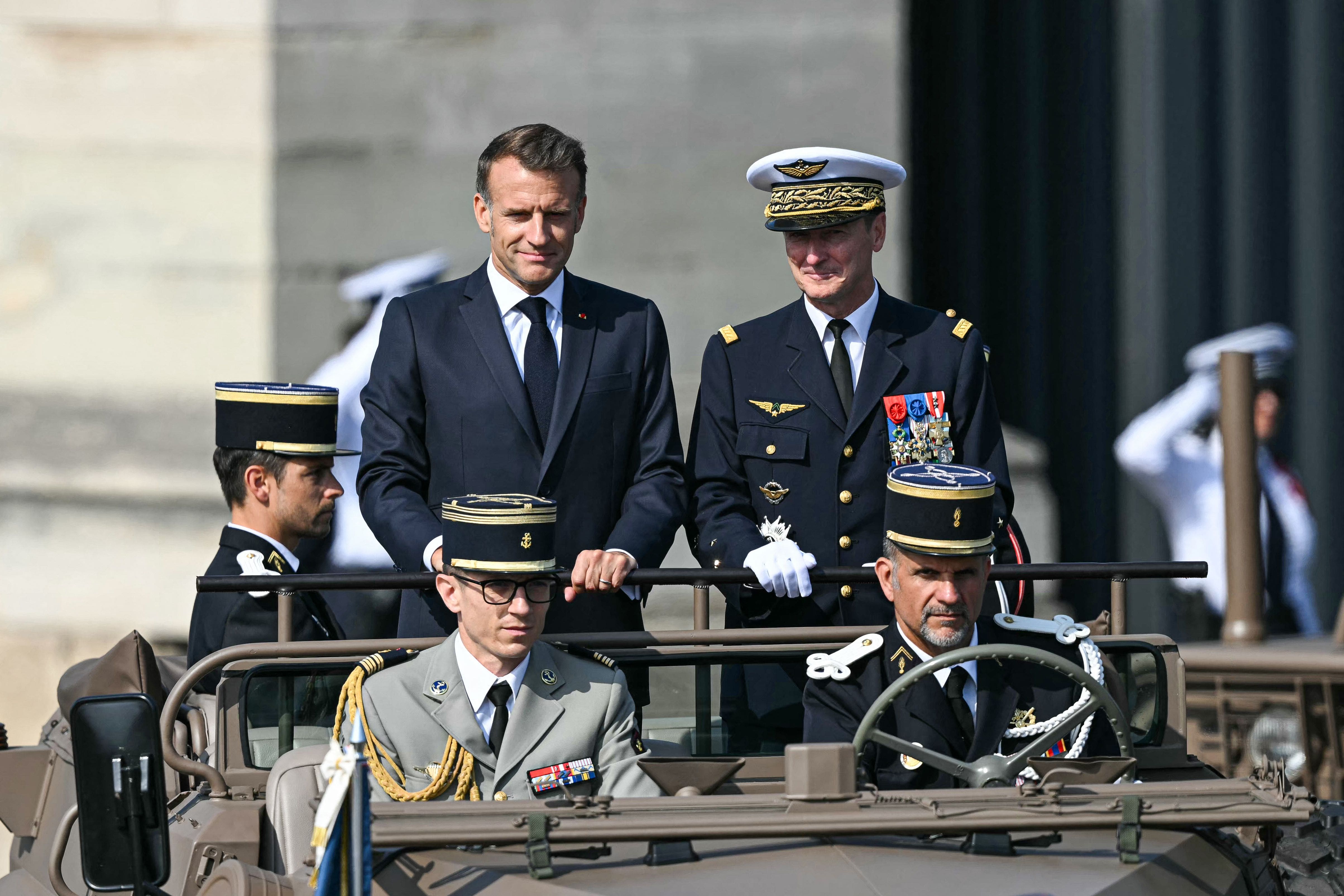 French President Emmanuel Macron (CG) parades aboard the command vehicle alongside Chief of Defense Staff Fabien Mandon (CD) during the annual Bastille Day military parade on Avenue des Champs-&Eacute;lys&eacute;es in Paris, July 14, 2026.