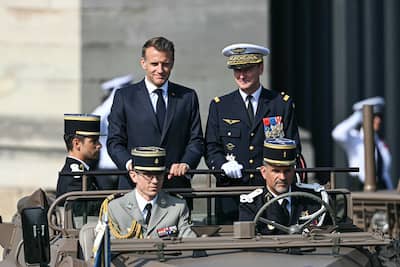 French President Emmanuel Macron (CG) parades aboard the command vehicle alongside Chief of Defense Staff Fabien Mandon (CD) during the annual Bastille Day military parade on Avenue des Champs-Élysées in Paris, July 14, 2026.