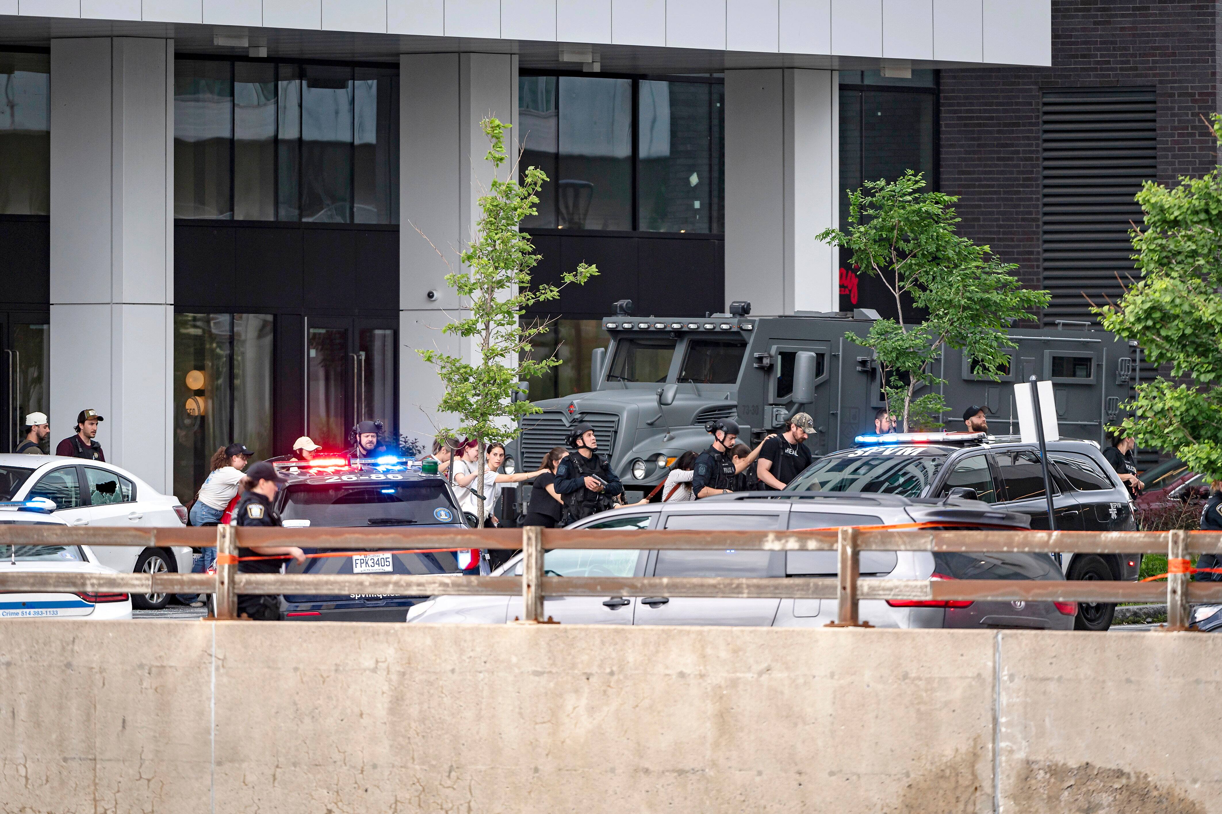 Des citoyens évacuant la scène sous la protection des policiers.