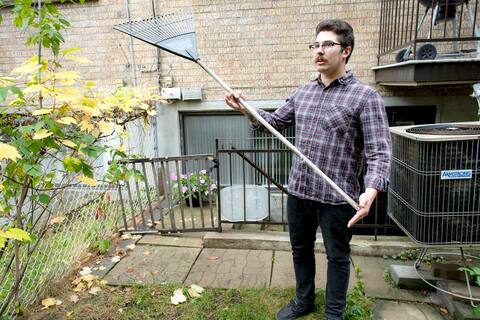 Justin Addison mostra con le sue mani la lunghezza della fessura tra il suo cortile e il suo edificio.