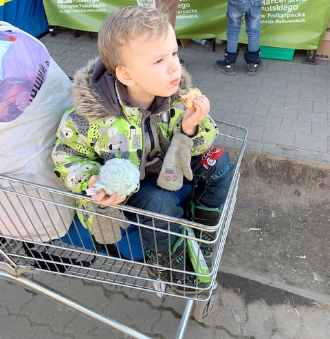 Un niño utilizó una cesta de la compra para descansar las piernas mientras cruzaba la frontera con Polonia.