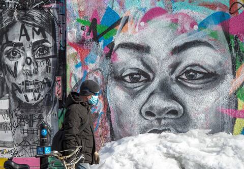 Un hombre con mascarilla camina por la acera en Montreal en marzo de 2021.