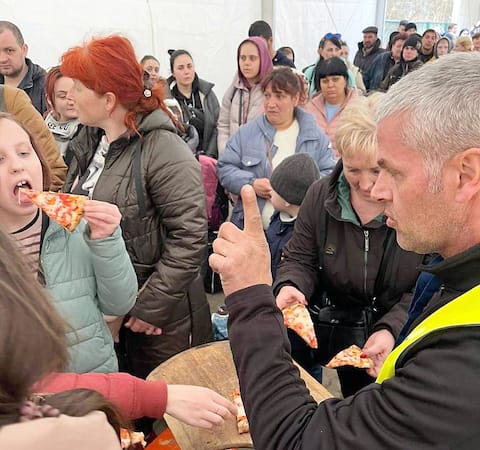 Pan Fournier rozdaje pizzę ukraińskim uchodźcom.