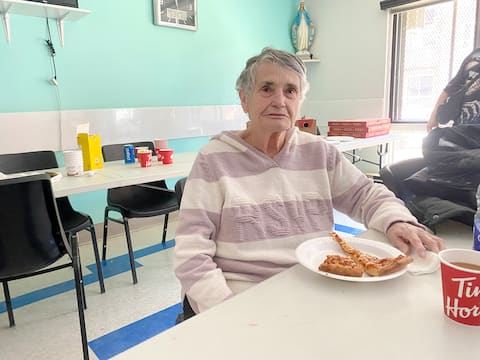 Monique Bélisle, president of HLM's residents group, eats pizza brought in by citizens helping HLM.