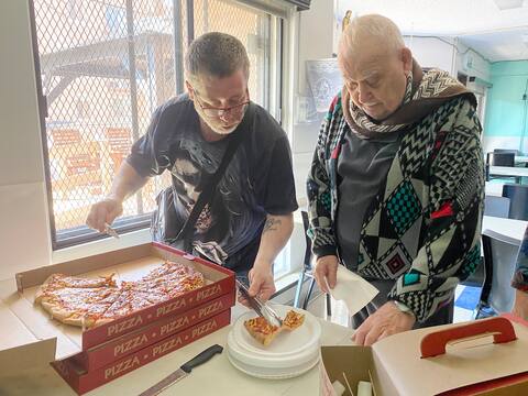 Good Samaritan citizen Claude Ducharme delivers pizza brought by citizens helping HLM to Jean-Paul Ménard.