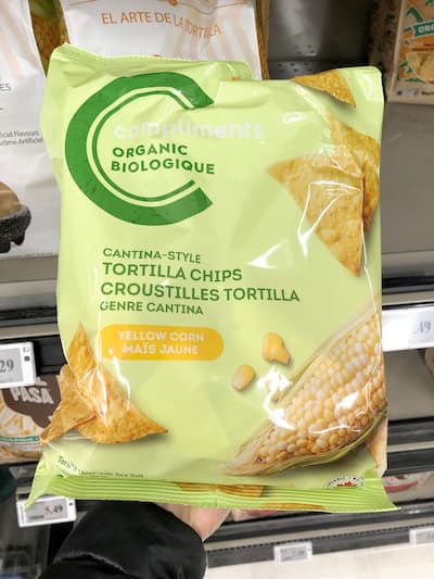 People eating tasty corn chips at white table