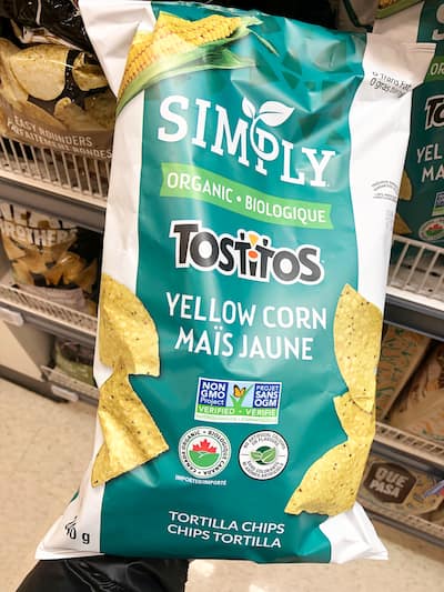 People eating tasty corn chips at white table