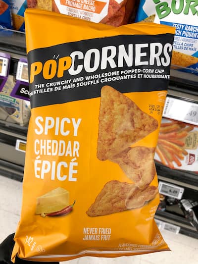 People eating tasty corn chips at white table