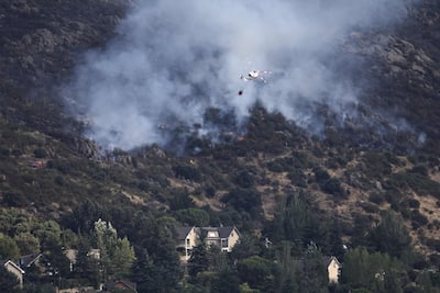 A photo taken on July 25, 2026 shows a firefighting helicopter dropping water as a wildfire in the mountains threatens to approach the village of Robledo de Chavela, 60 km west of Madrid.