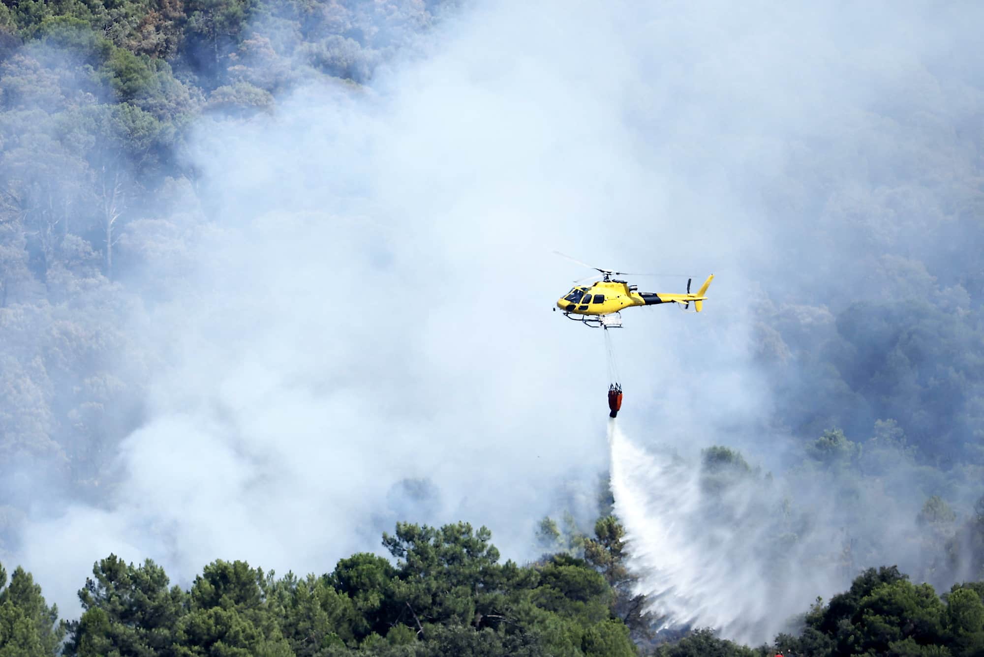 A helicopter tries to put out forest fires 70 km west of Madrid on Sunday.