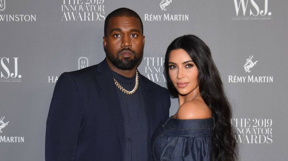 Kanye West sourit à la caméra, alors qu'il assiste à un événement en compagnie de son amoureuse, Kim Kardashian West.