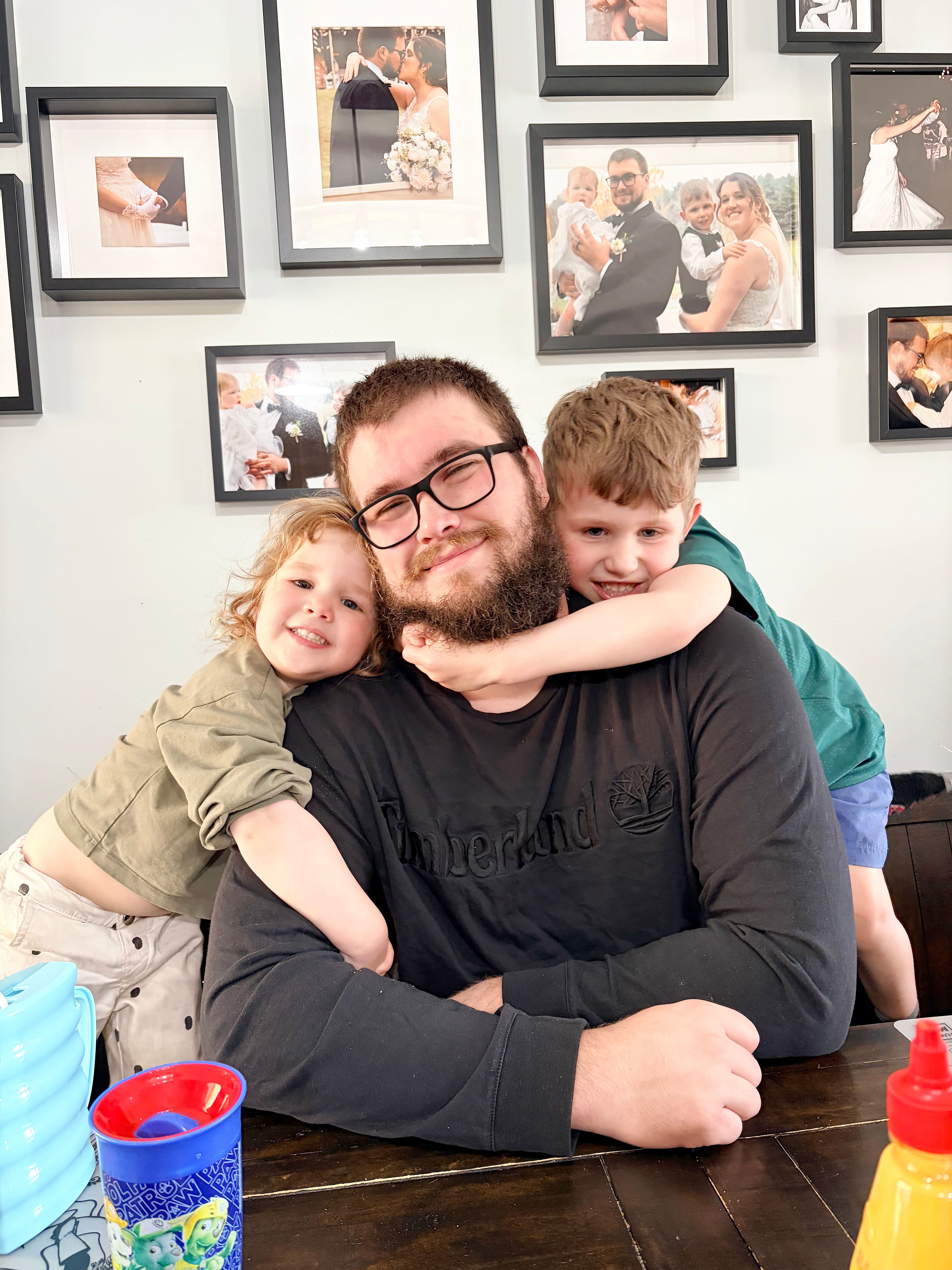 Tomy Durand et ses deux enfants, Elena et Arthur, devant les photos familiales de mariage en mai 2026.