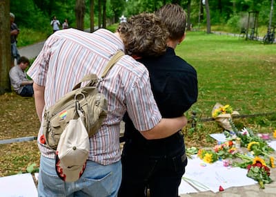 A couple embrace at a makeshift memorial site for the victims on July 26, 2026, near the scene in Berlin's Tiergarten park where a car was driven into people the previous evening, killing one person and injuring 16 others on the sidelines of the Christopher Street Day (CSD) parade.