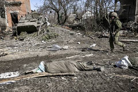 A soldier crosses the body of a Russian soldier following the Ukrainian army took over the village of Mala Rogan, east of Kharkiv.