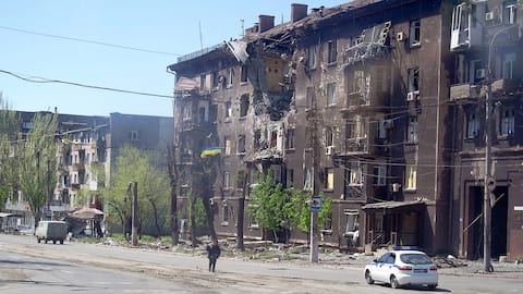 A man walks past a dilapidated residential building in Mariupol on Friday.
