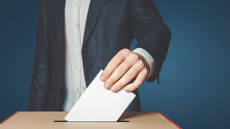 Man Voter Putting Ballot Into Voting box. Democracy Freedom Concept On Blue Background With Copy-Space