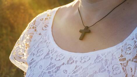 Chain with a cross on a neck . Christian cross on sunset background . Religion background . Paradise heaven . Light in sky . Happy Easter .