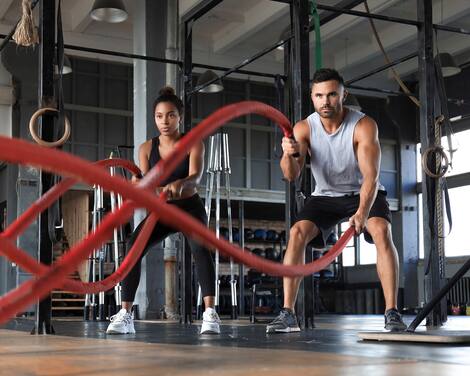 Athletic young couple with battle rope doing exercise in functional training fitness gym. Athletic young couple with battle rope doing exercise in functional training fitness gym.