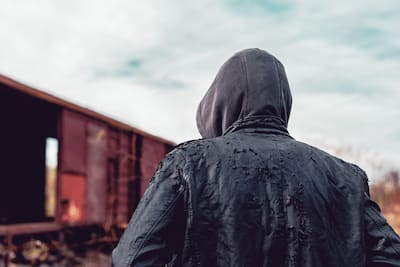 Homeless immigrant walking by freight train wagons