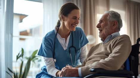 Caring female nurse in blue scrubs smiling and holding hands with an elderly male patient Caring female nurse in blue scrubs smiling and holding hands with an elderly male patient