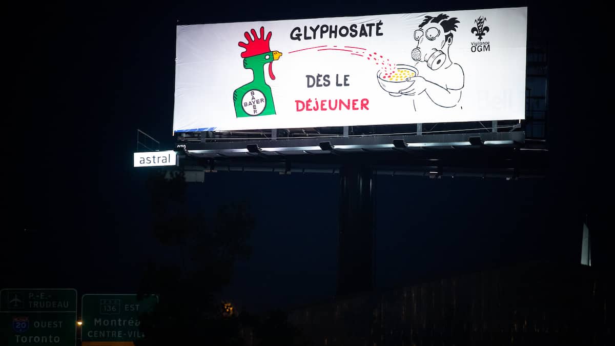 Vigilance OGM escalade un panneau publicitaire et y installe sa bannière