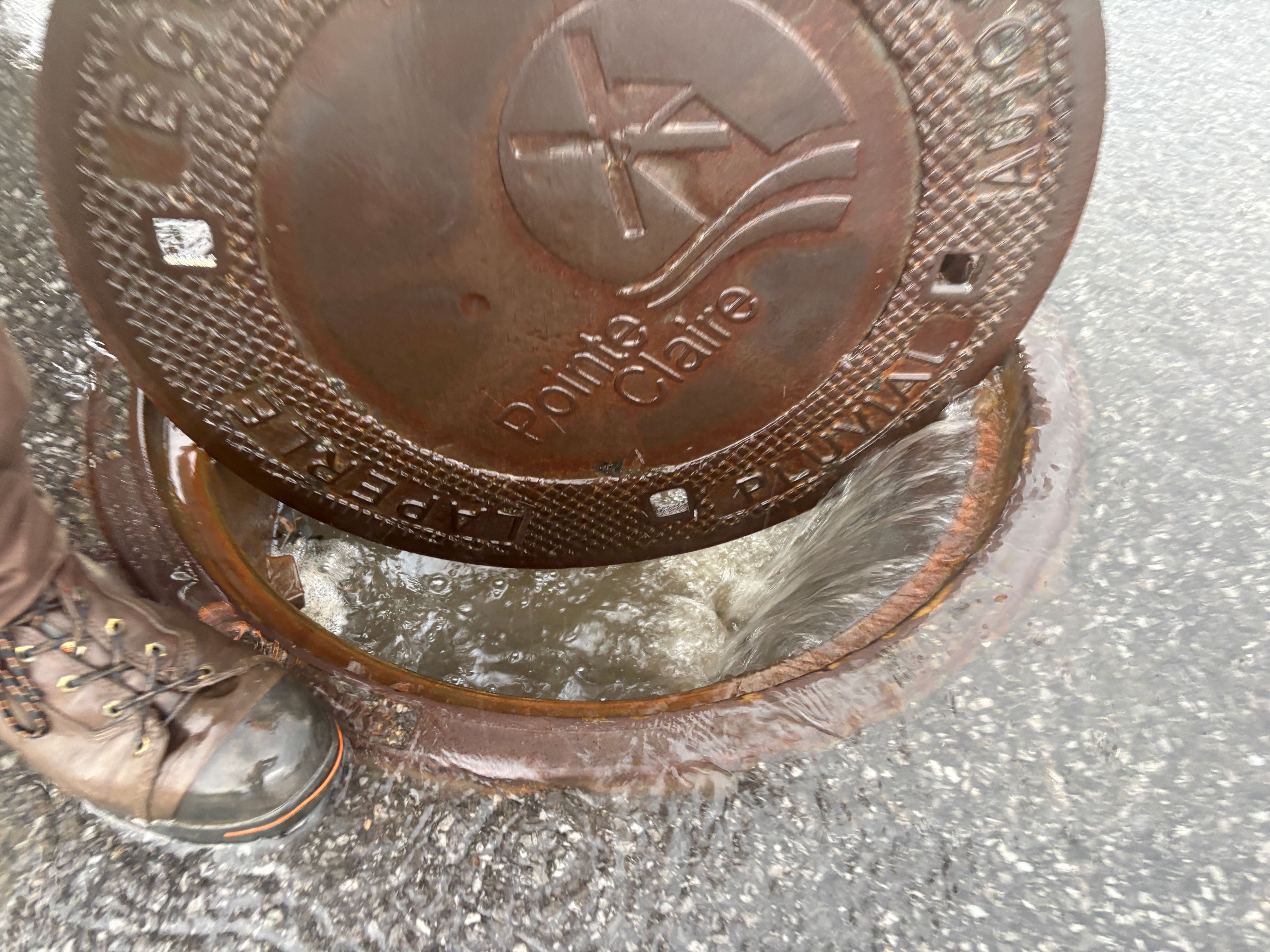 Une bouche d’égout a carrément sauté à Pointe-Claire en raison des inondations, le 20 juin 2026.
