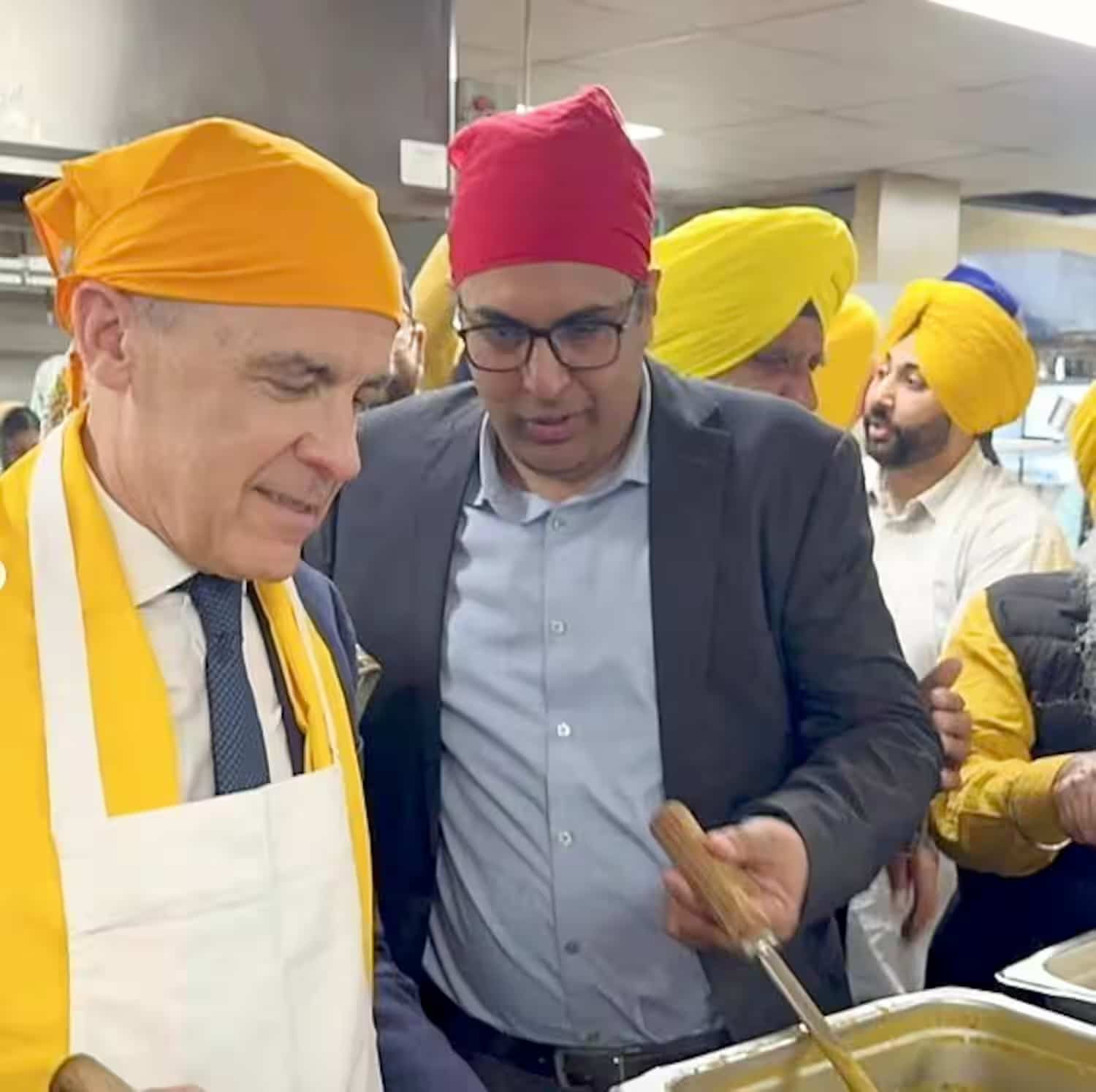 Mark Carney (foulard jaune) le 13 avril 2025, lors de la campagne fédérale, participe à un événement communautaire sikh en compagnie de Tej Dulat (foulard rouge).