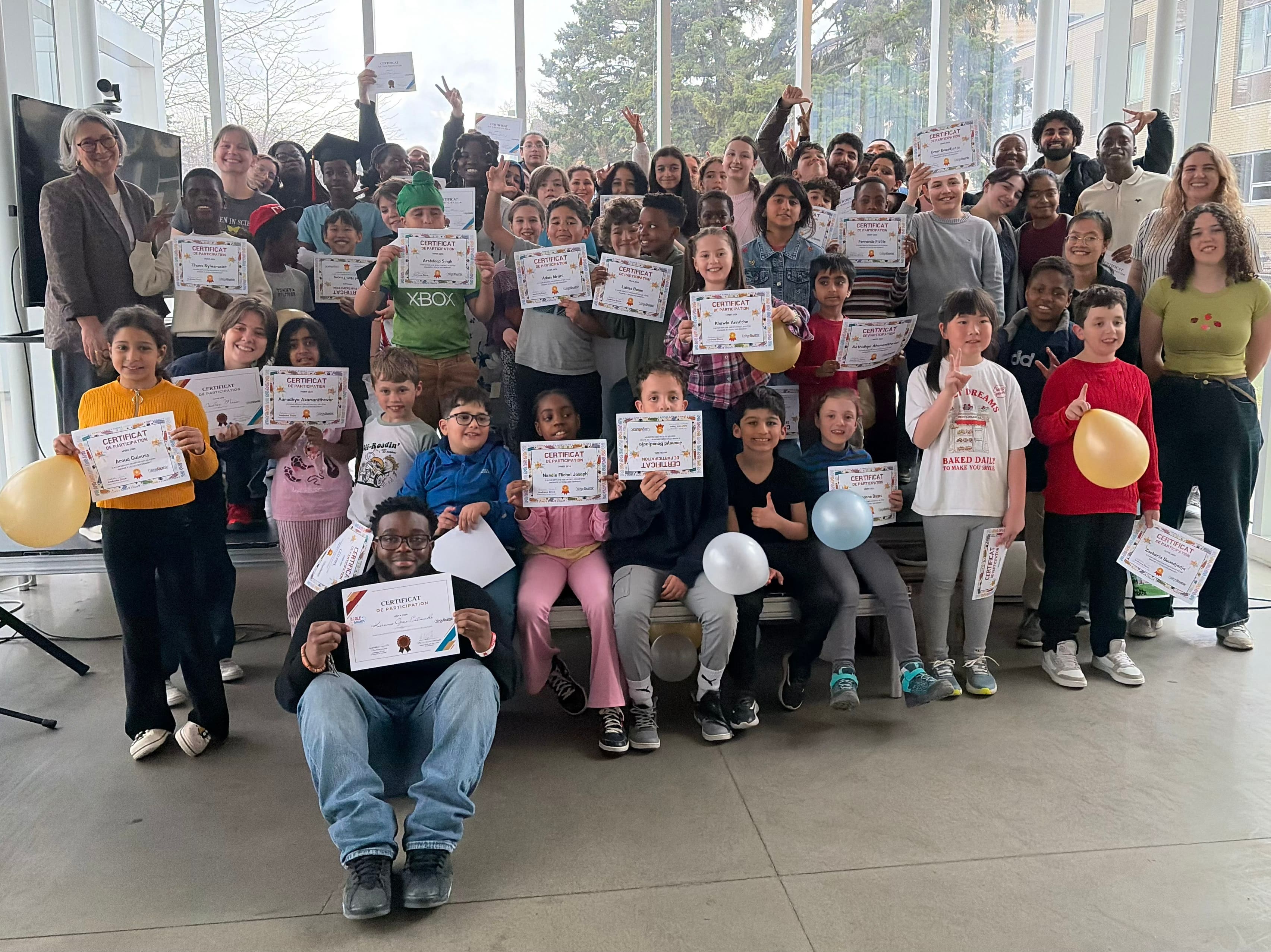 Kervens Gino Estimable, mentor assis à l'avant de la photo, en compagnie des élèves qui ont reçu leur diplôme lors de la cérémonie au Collège Ahuntsic à l'automne 2025.