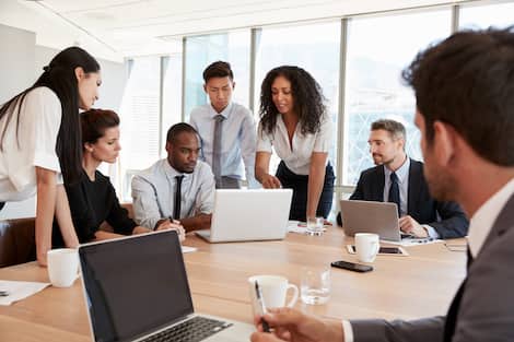 Group Of Businesspeople Meeting Around Table In Office Group Of Businesspeople Meeting Around Table In Office