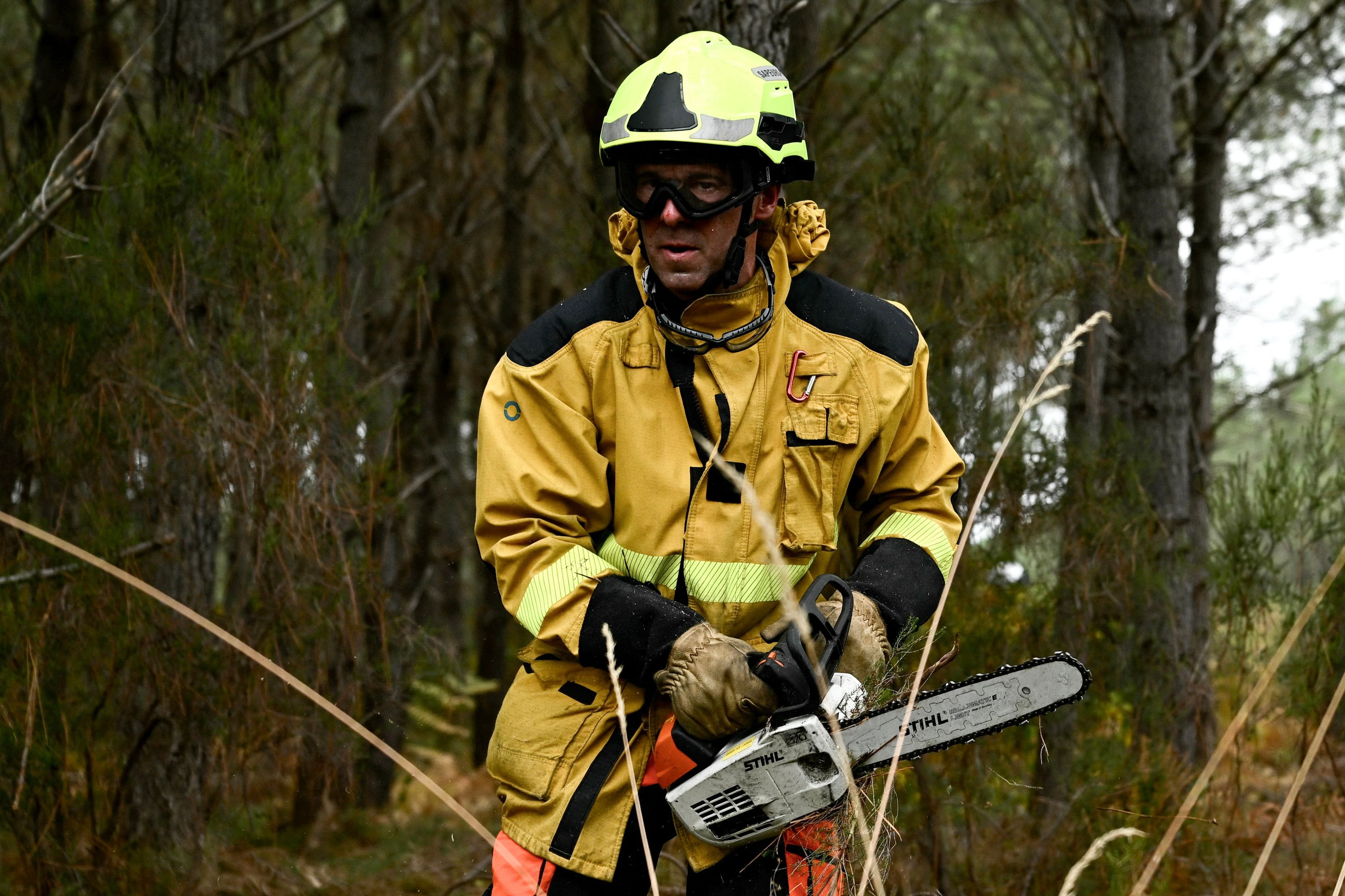A firefighter clears brush in Saint-Jean-d'Illac, west of Bordeaux, on July 27, 2026, during forest fires in the Gironde region, southwest of France.