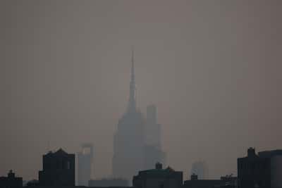 Haze from Canadian wildfires covers the Manhattan skyline, including the Empire State Building, as seen from Brooklyn Bridge Park on July 17, 2026 in New York. New York City is under an air quality health advisory as smoke from wildfires in Canada and the Great Lakes region gradually spreads across the region, creating a thick haze in the heat.