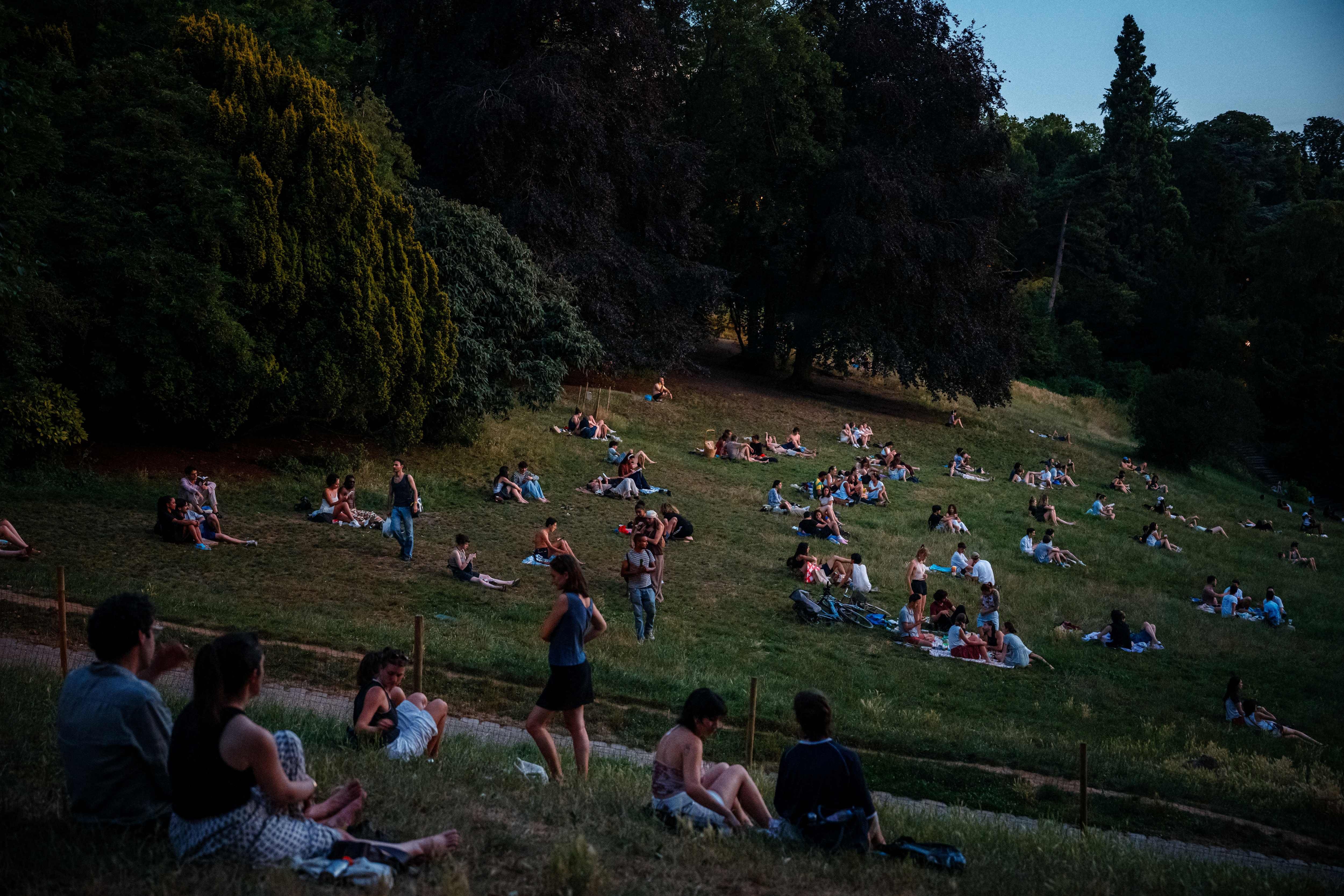 Au Parc des Buttes-Chaumont à Paris, en fin de journée le 25 juin 2026, des gens s'assoient sur l'herbe pour se mettre à l'abri de la chaleur, alors que la France est en proie à une vague de chaleur.