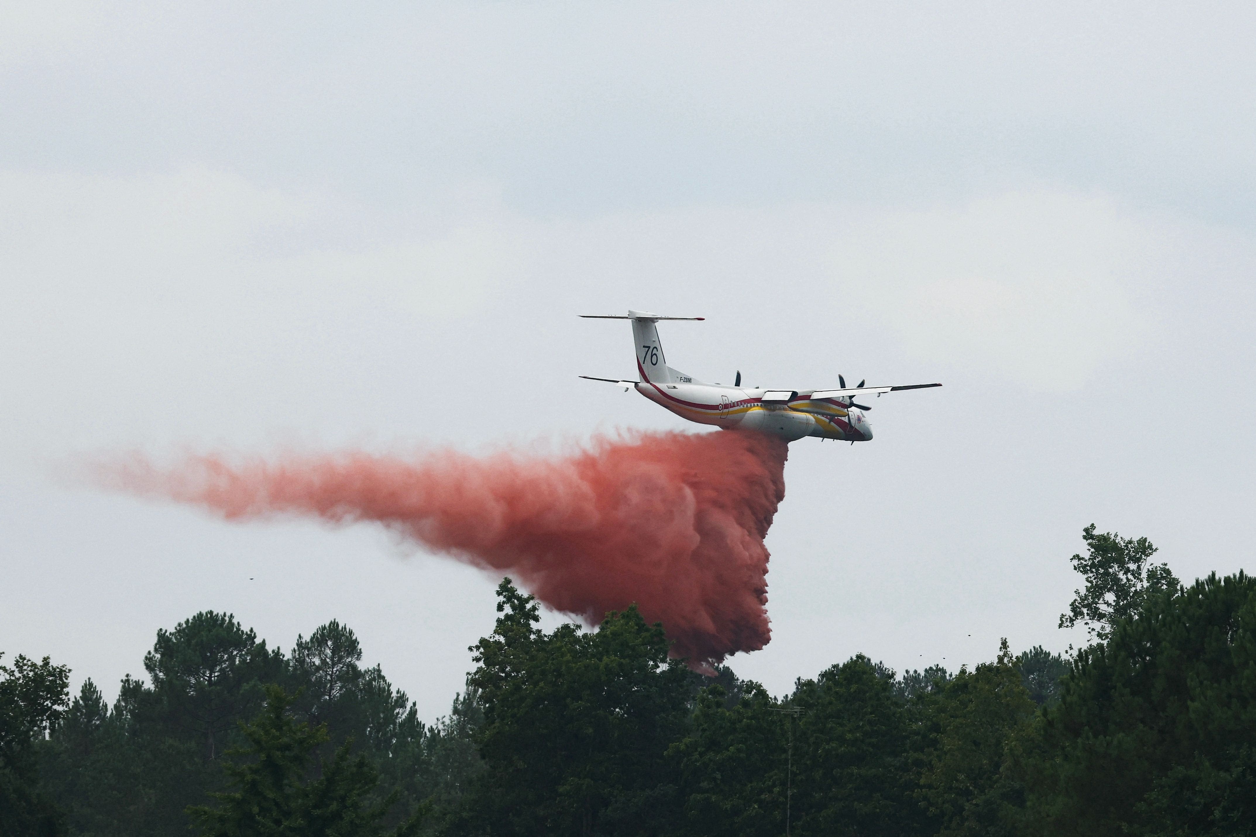 This photograph shows a Bombardier Dash 8 Q400 MR aircraft (right) dropping retardant on a forest near Marcheprime, about 30 km from Bordeaux, on July 27, 2026, as a forest fire ravages Gironde, in southwest France.