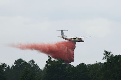 This photograph shows a Bombardier Dash 8 Q400 MR aircraft (right) dropping retardant on a forest near Marcheprime, about 30 km from Bordeaux, on July 27, 2026, as a forest fire ravages Gironde, in southwest France.