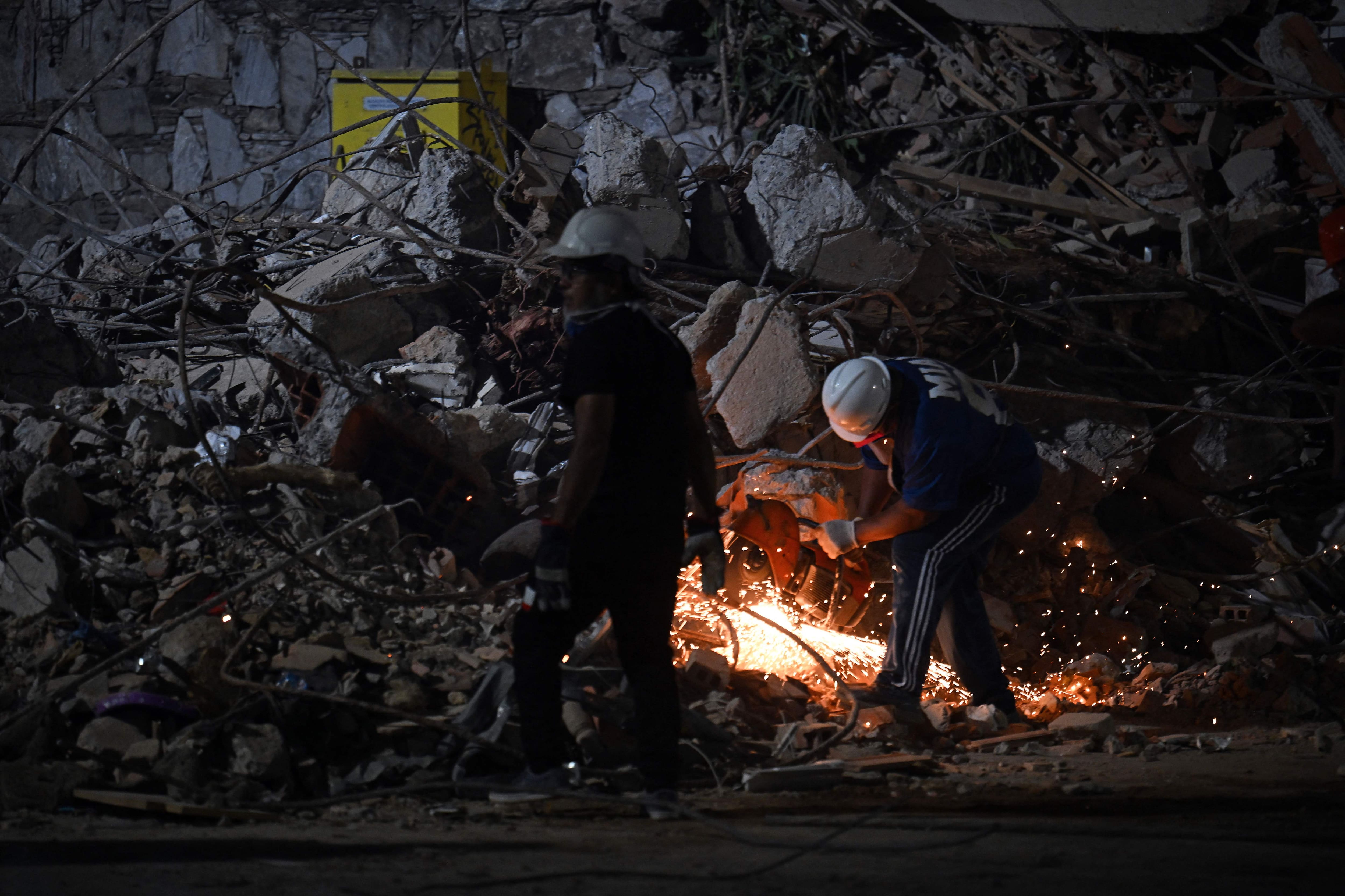 In Caracas, on June 25, 2026, a rescuer cuts the steel bars of a collapsed building using an angle grinder, following deadly earthquakes.