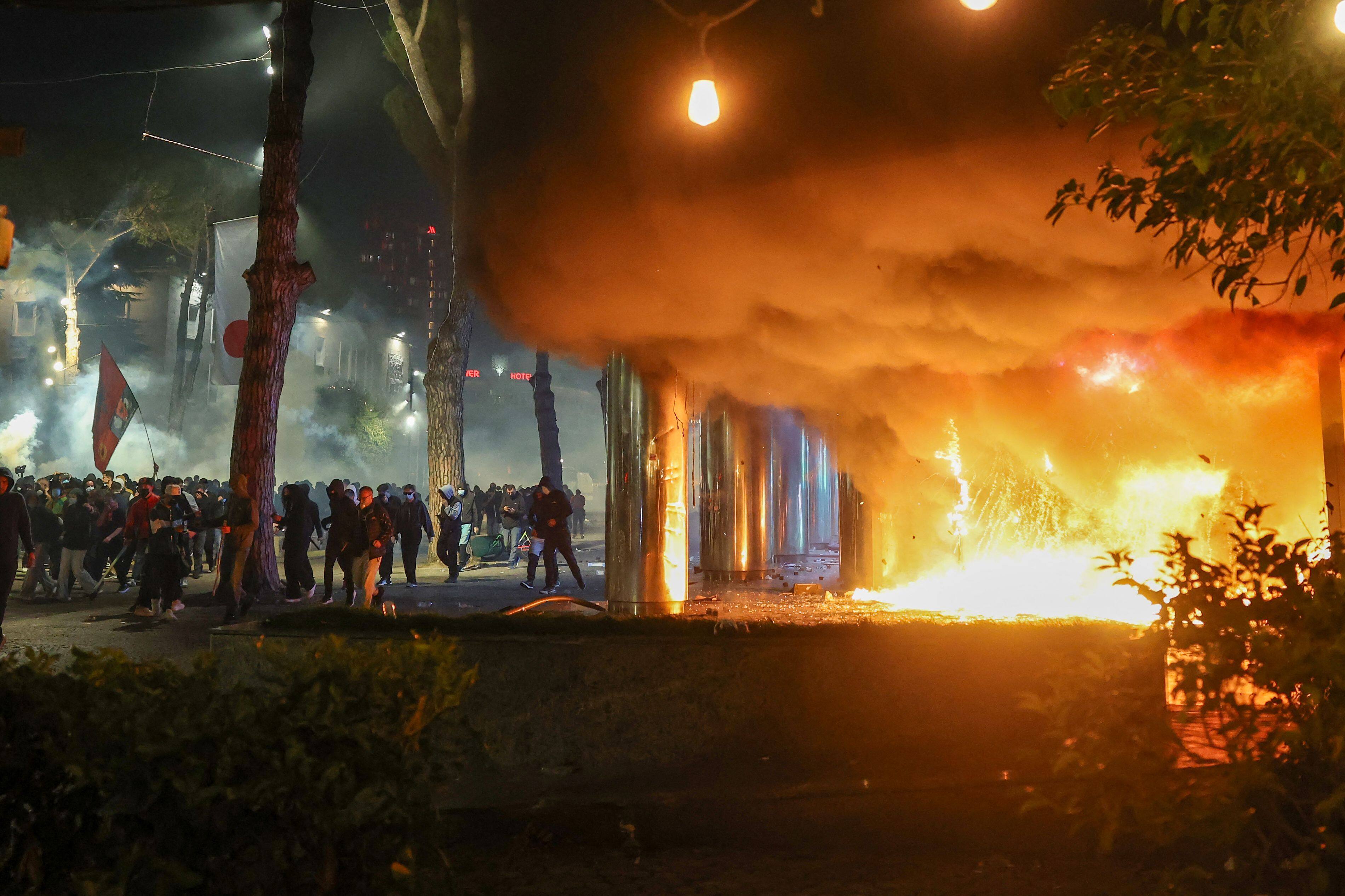 De la fumée s'élève d'un incendie près d'un groupe de manifestants lors d'affrontements avec la police anti-émeute dans le centre de Tirana, en Albanie, le 14 octobre 2026.