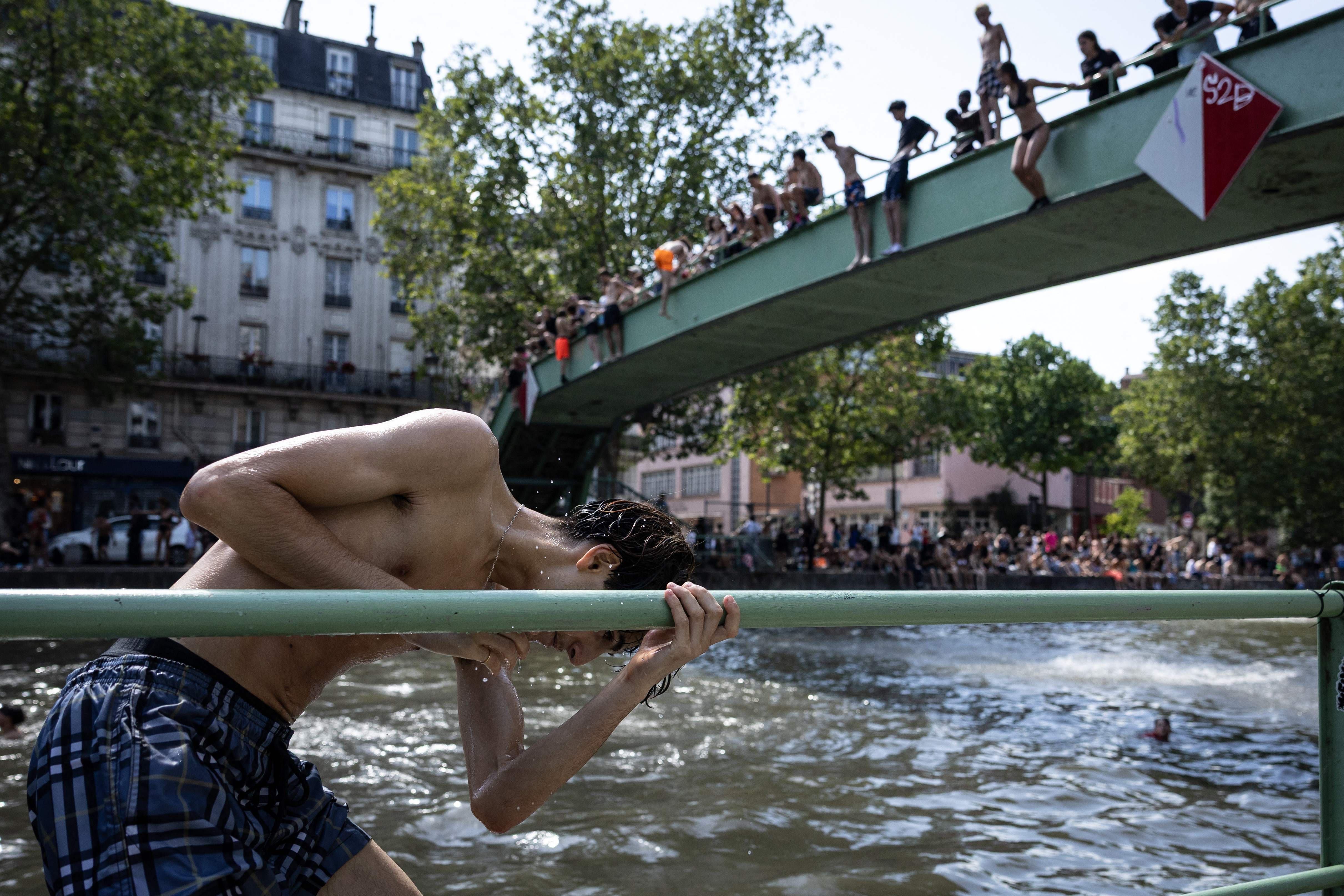 Des jeunes plongent dans le canal Saint-Martin lors d'une vague de chaleur à Paris, le 24 juin 2026.
