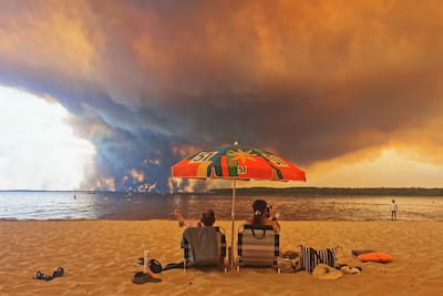 Boaters relax on Moutchic beach, located about fifty kilometers from Bordeaux, in the southwest of France, on July 24, 2026, in an end-of-the-world atmosphere with the gigantic forest fire opposite.