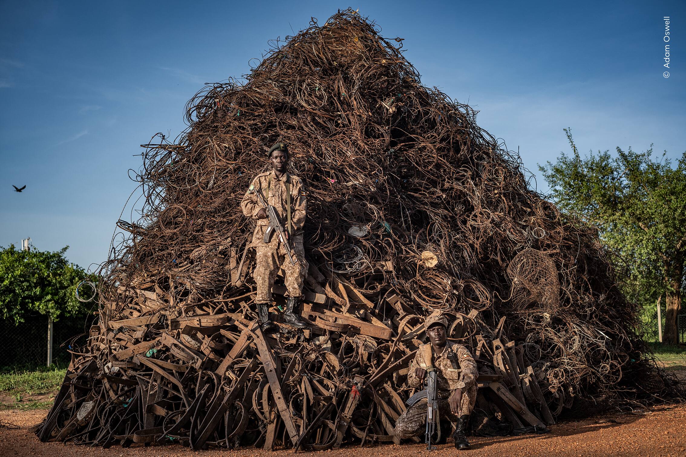 Un amas impressionnant de pièges confisqués gît derrière les gardes forestiers de l’Autorité ougandaise de la faune sauvage.